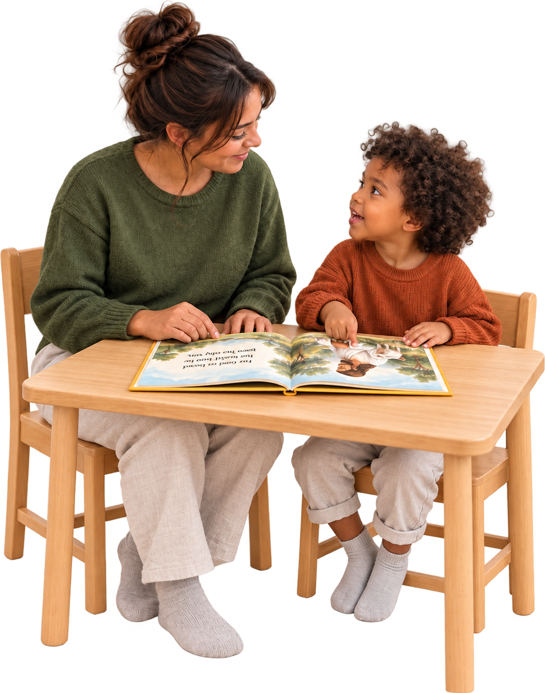 A teacher and a three-year-old at a small wooden table, an open picture book between them showing the Good Shepherd carrying a lamb; the child is pointing at the page and looking up at the teacher, who is smiling at the child
